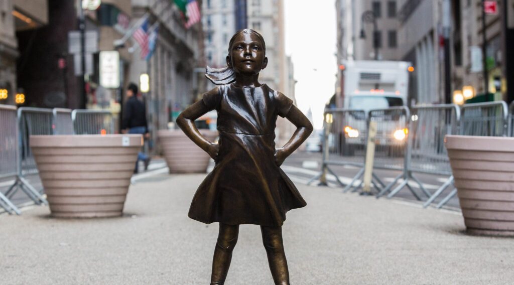 Fearless Girl statue standing confidently in front of the New York Stock Exchange, symbolizing strength and empowerment.