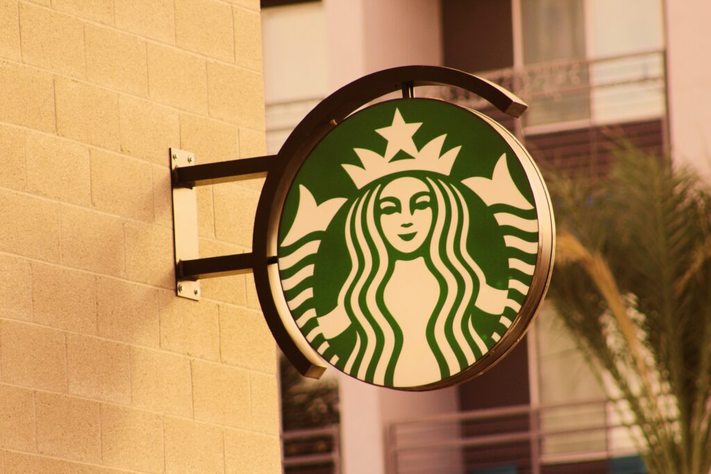 Starbucks logo displayed outside a store, featuring its signature green color, reflecting the brand’s commitment to sustainability and a connection to nature.