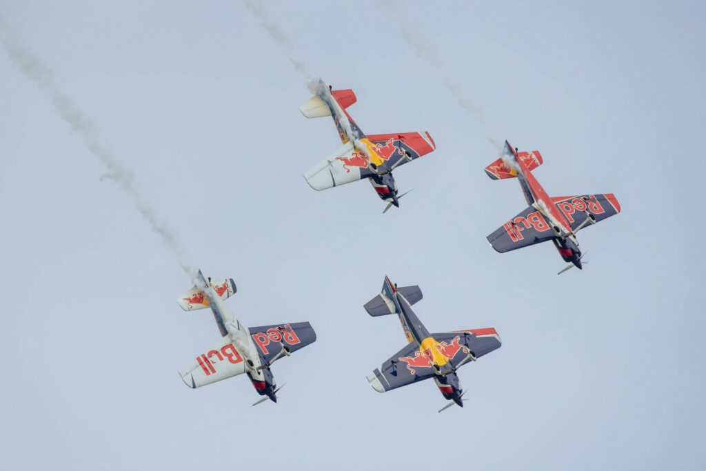 Planes performing aerial tricks in a Red Bull airshow, showcasing the brand's association with extreme sports and high-energy events.