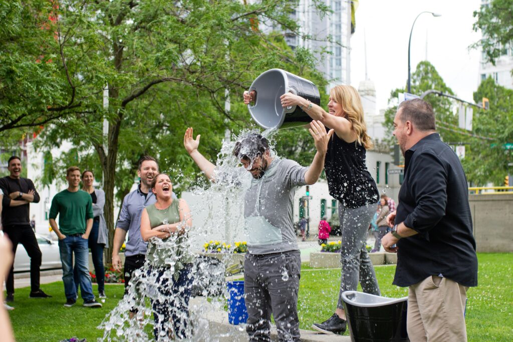 A group of people enthusiastically participating in the Ice Bucket Challenge, pouring ice water over their heads while laughing and cheering.