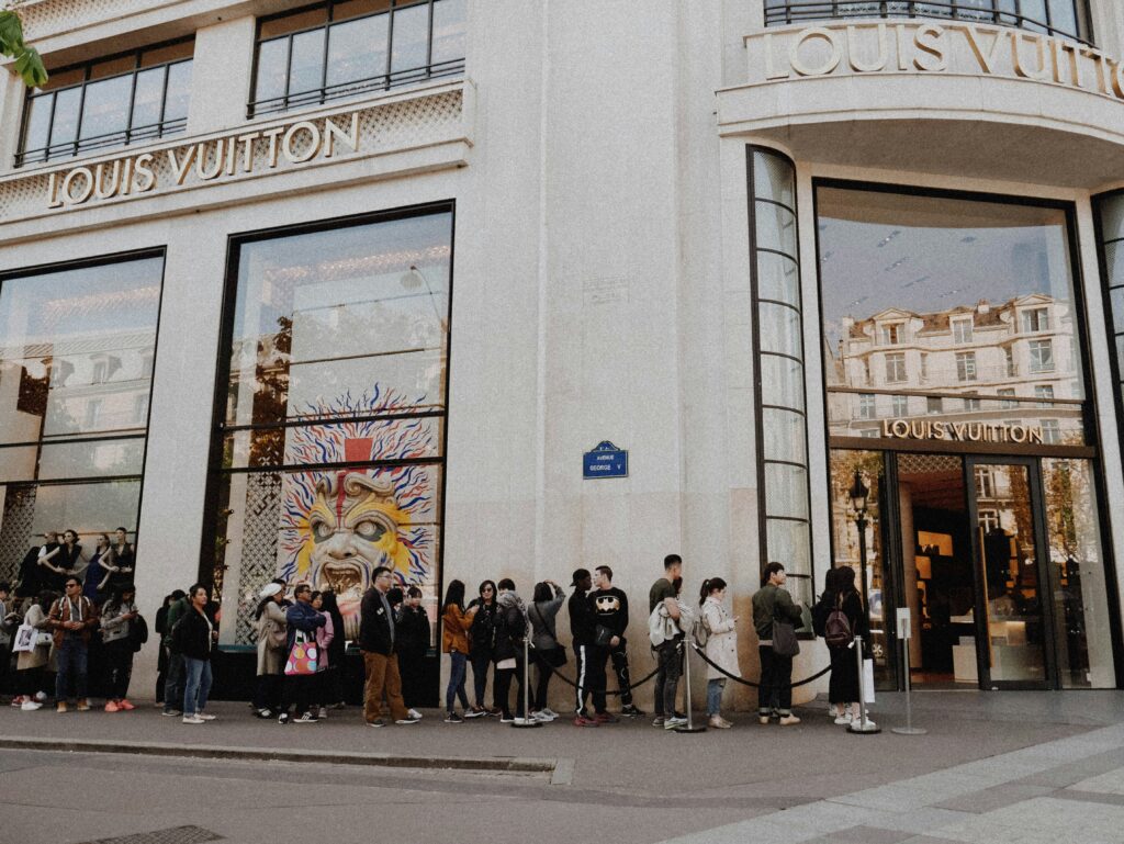 Louis Vuitton store with a line of eager customers outside, highlighting exclusive offers and the sense of privilege associated with limited-edition releases and luxury shopping experiences