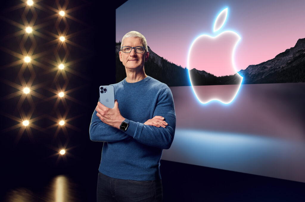 Steve Jobs presenting at an Apple product launch event with the iconic Apple logo displayed behind him.