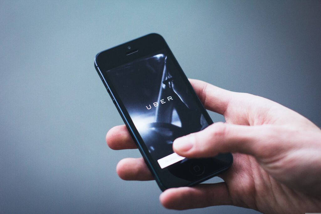 Person holding a smartphone with the Uber app open, showcasing the company's referral marketing strategy