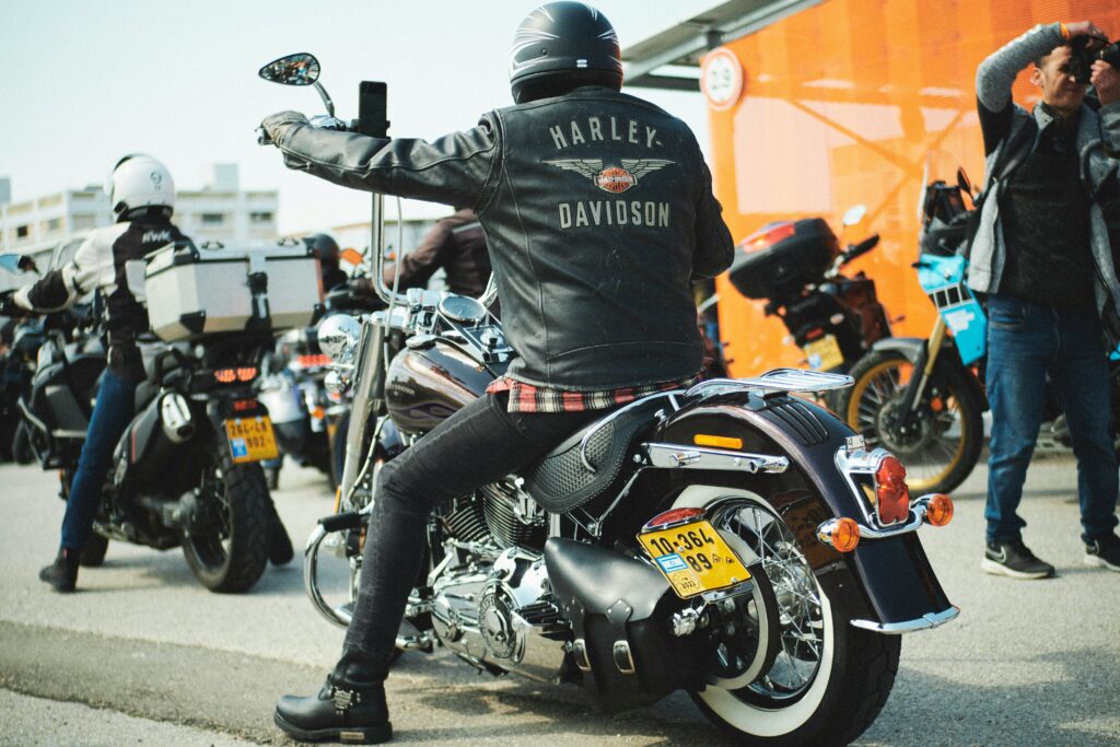 A person sitting on a Harley-Davidson motorcycle, showcasing the brand's iconic status.