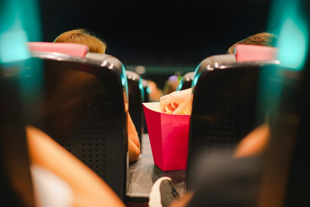 A movie theater scene featuring a person enjoying popcorn while watching a film.