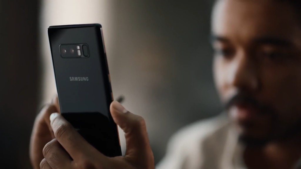 Man smiling while holding a Samsung Galaxy phone, representing the transition from an iPhone user.