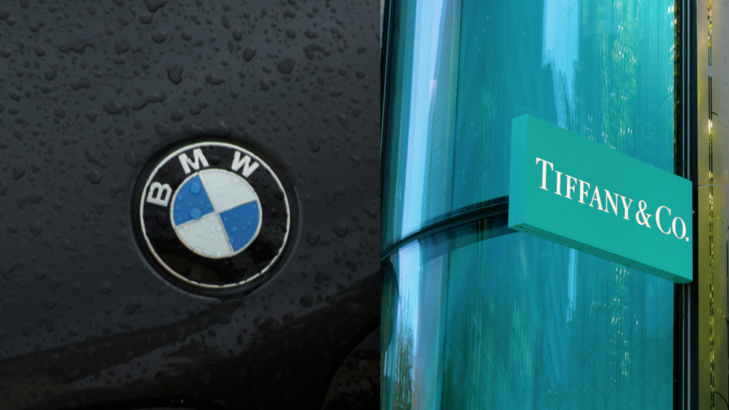 BMW logo on a car alongside Tiffany & Co. logo outside a store.