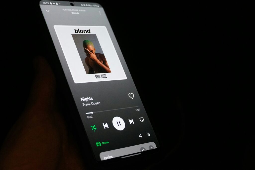 A black background featuring a smartphone displaying the Spotify app, highlighting micro white space around song titles and controls for improved readability.