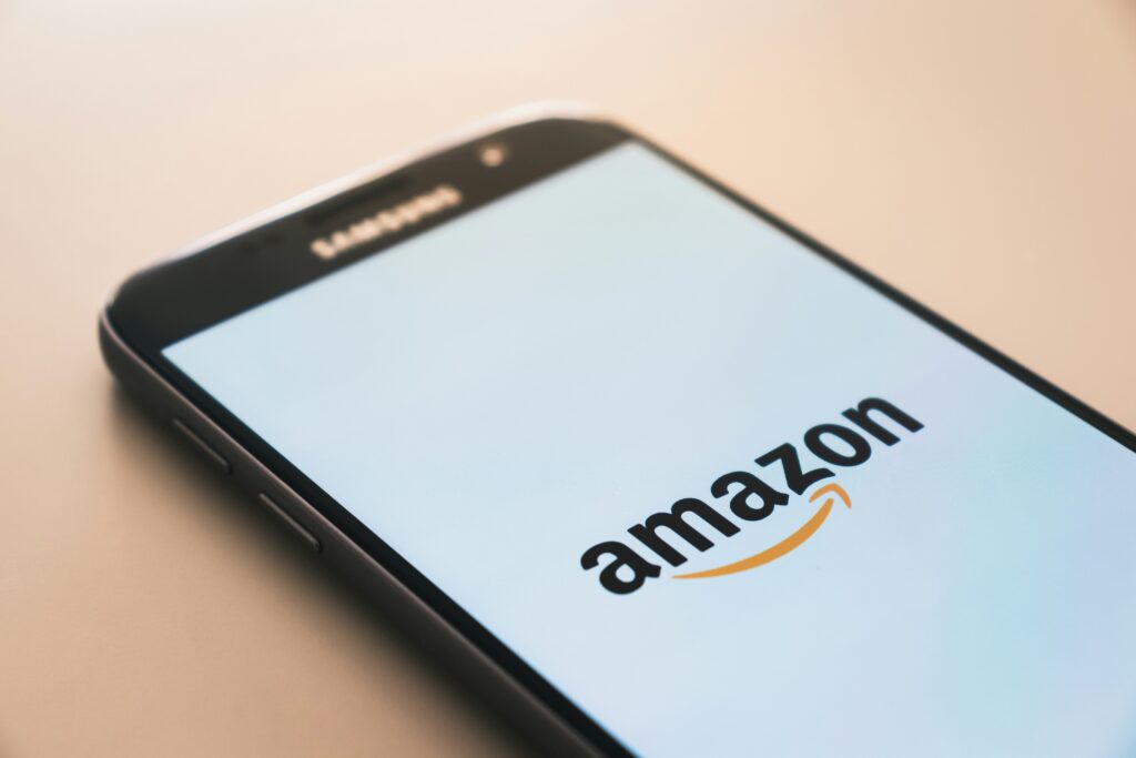 Amazon logo displayed on a smartphone, illustrating the brand's relevance of the brand symbol and connection to online shopping experience.