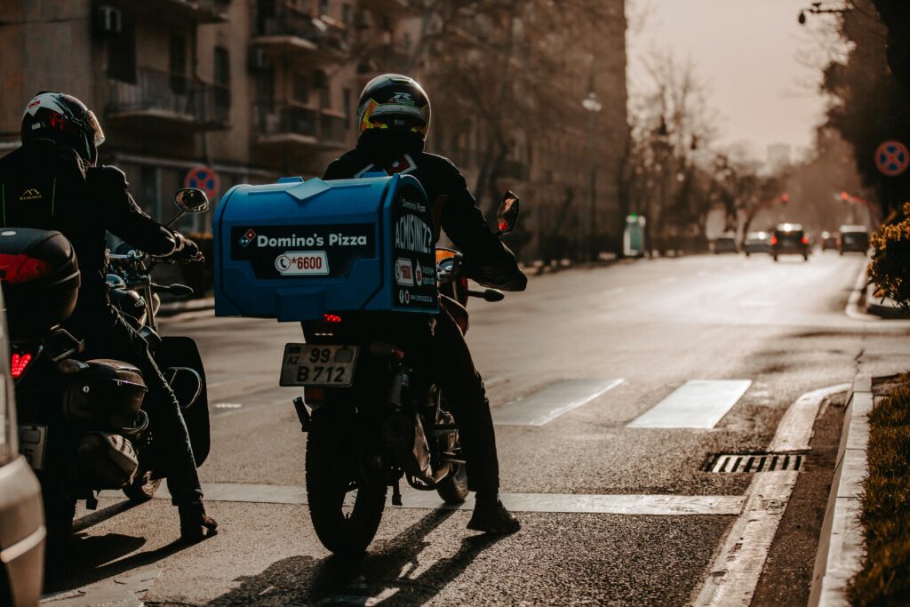 A Domino's delivery driver delivering a pizza to a customer's doorstep, using "Piece of the Pie" through mobile marketing.