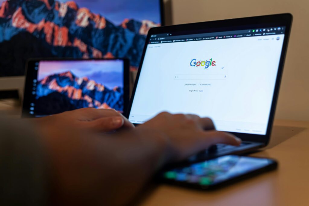 A person using a laptop with the Google homepage open, showcasing ample macro white space around the search bar and other elements for improved navigation.