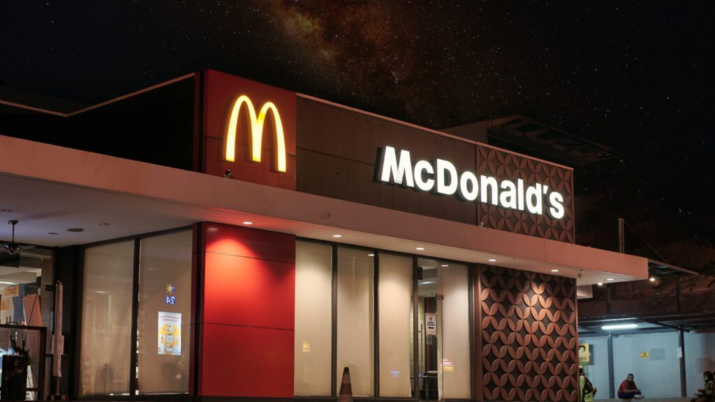 Exterior view of a McDonald's restaurant, showcasing its iconic branding and drive-thru service in a busy urban area with people targetted by geomarketing.