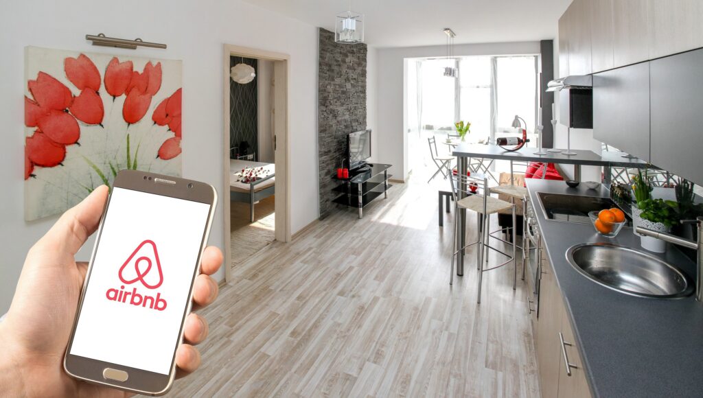 A man holding a phone with the Airbnb app open, showcasing immersive branding through unique travel experiences.