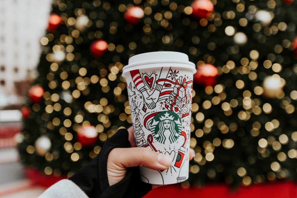 A Starbucks store exterior featuring the logo and "Starbucks Coffee" sign, alongside a person holding a bottle of Coca-Cola, illustrating effective seasonal marketing.