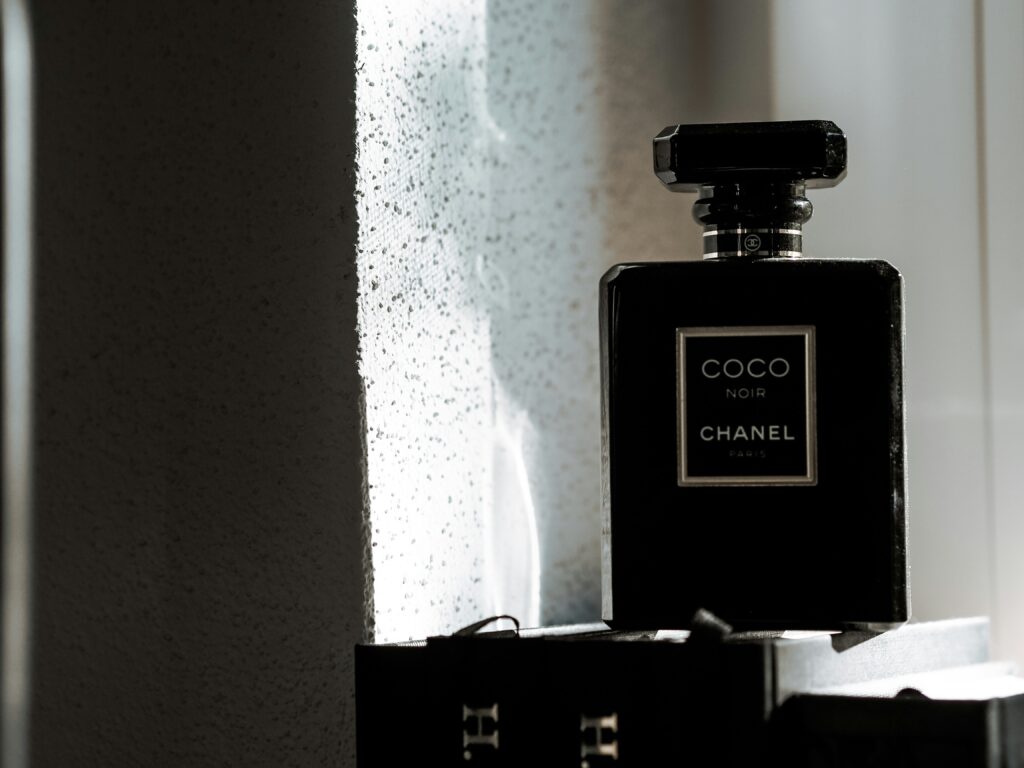  A stylish Chanel perfume bottle elegantly placed on a reflective surface, showcasing its luxurious design and the monochromatic color scheme.